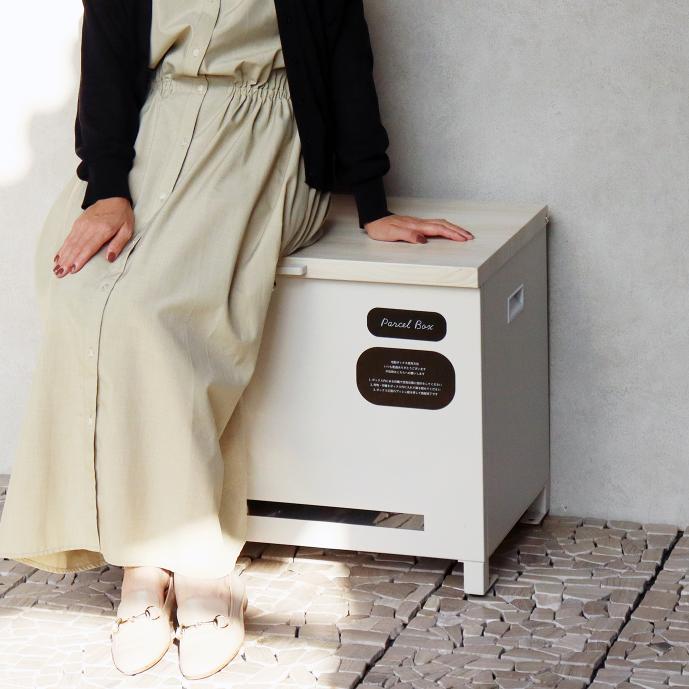 白い収納ボックスに腰掛ける女性